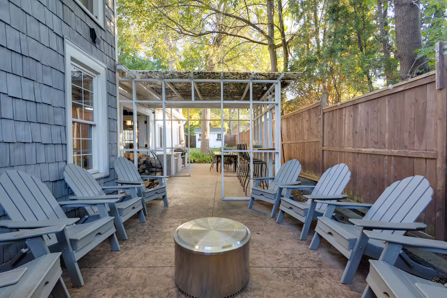 Shaded patio with Adirondack chairs, a pergola, and a fire pit